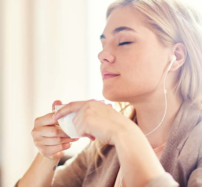 woman listening to music while sipping a cup of tea