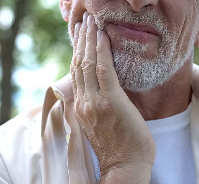 closeup of a man holding his jaw in pain
